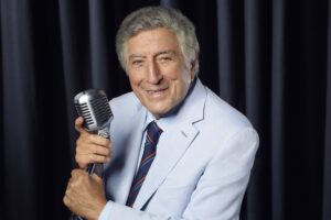 Tony Bennett sorrindo durante uma apresentação, enquanto sua família enfrenta uma disputa judicial por sua herança.